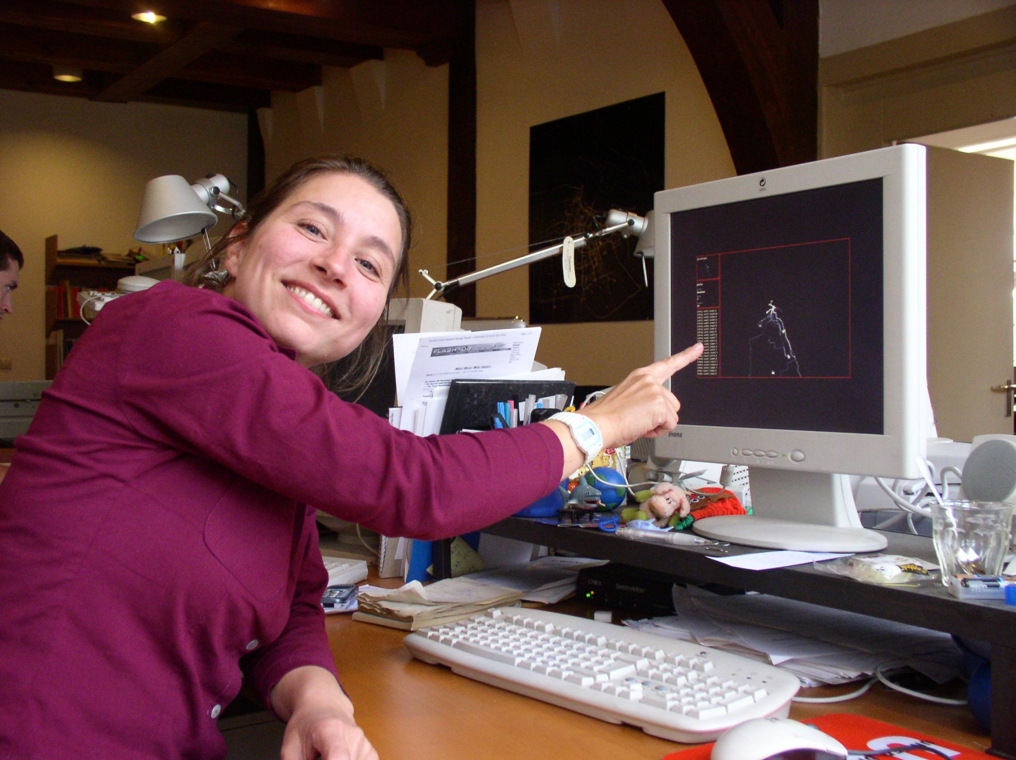 Esther smiles pointing at a computer screen showing the AmsterdamREALTIME interface