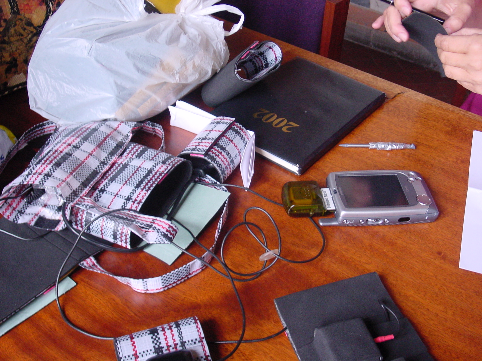 Table with a checkered carry bag, a PDA with GPS receiver and various cables